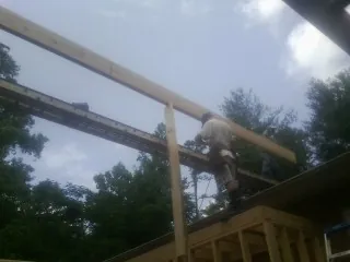 Carpenter setting a ridge beam over a new addition frame — Ice Dam Removal by Roofing Brothers in Walden