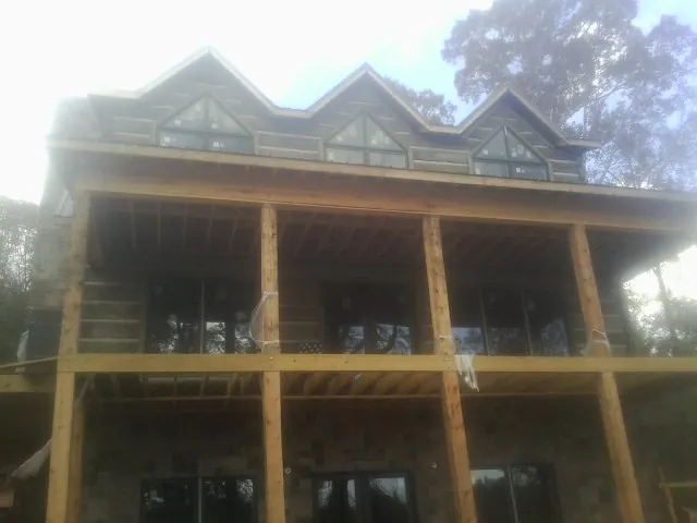 Dormers and porch framing on a large log home under construction — Roof Coating work by our crew in Walden