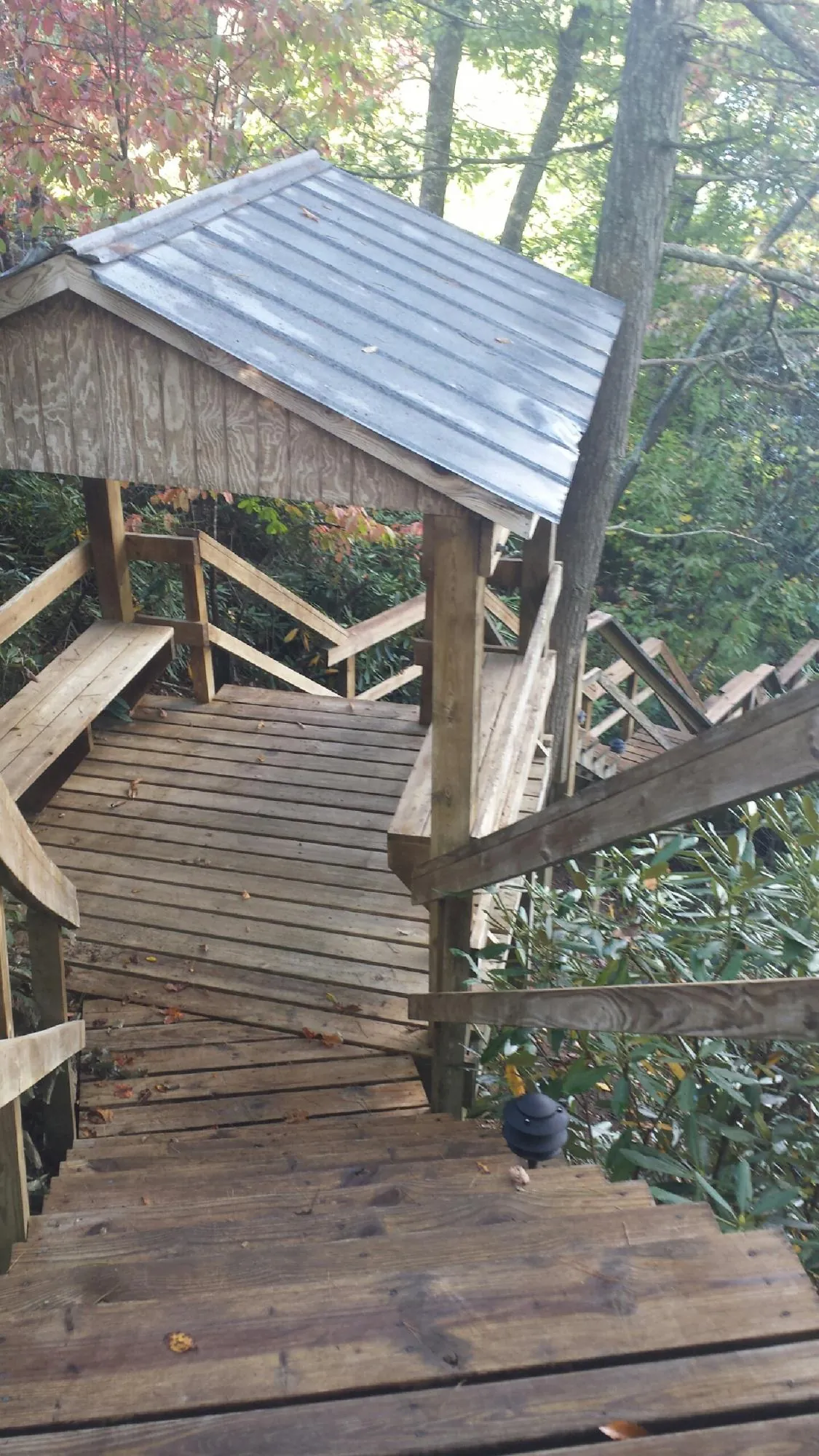 Metal roofed shelter over wooden steps on a wooded walkway — Skylight Repair & Installation work by our crew in Walden