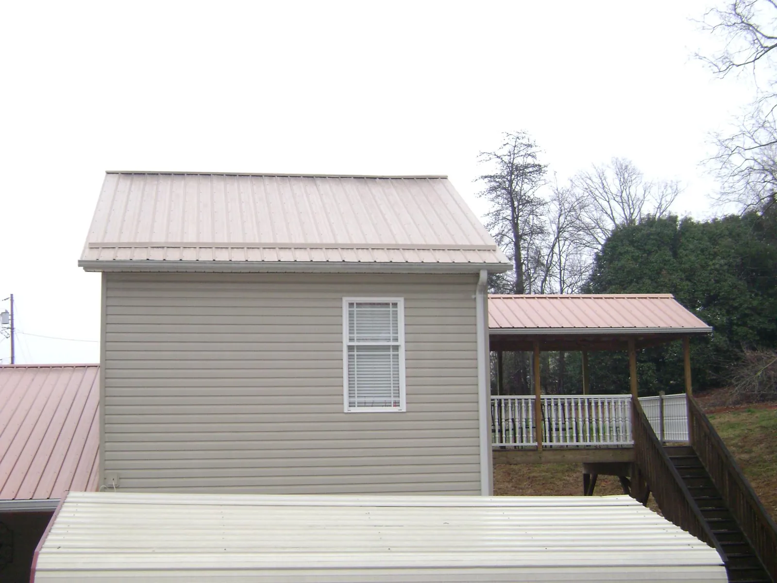 Tan metal roofs on a two story addition and attached porch, from a Roof Replacement job in Walden