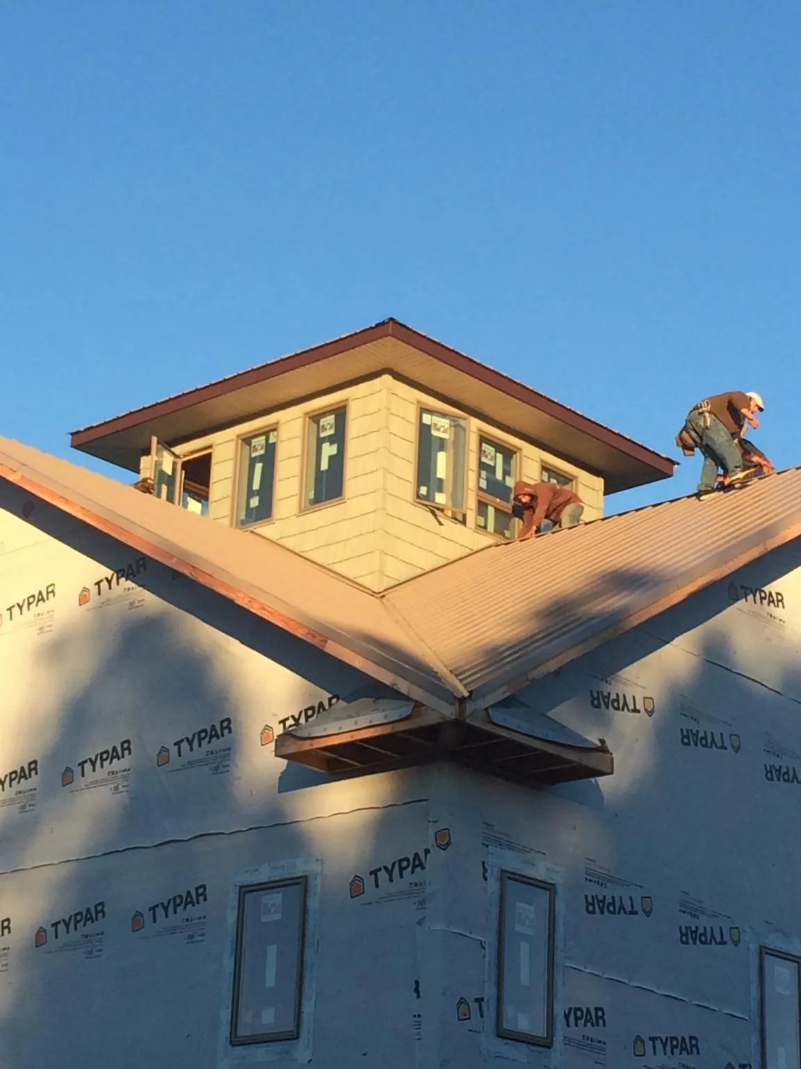 Roofers working around a rooftop cupola on a new metal roof at sunset — Roof Waterproofing in Walden by Roofing Brothers